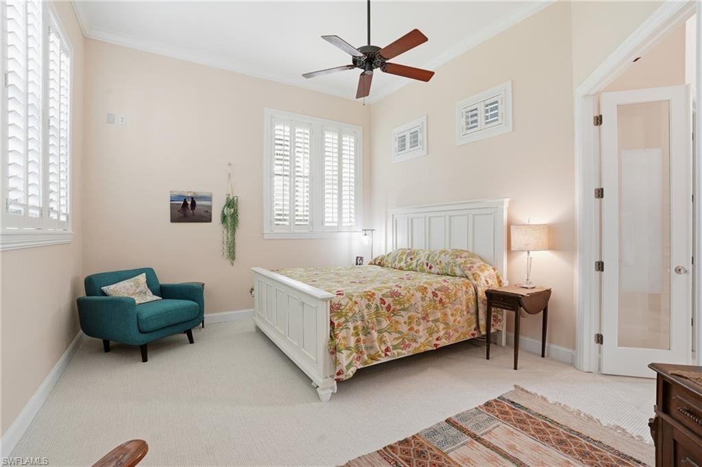 Bedroom with light carpet, ornamental molding, and a ceiling fan