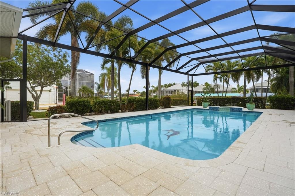 View of pool with a lanai, a patio, a pool with connected hot tub, and a sunroom