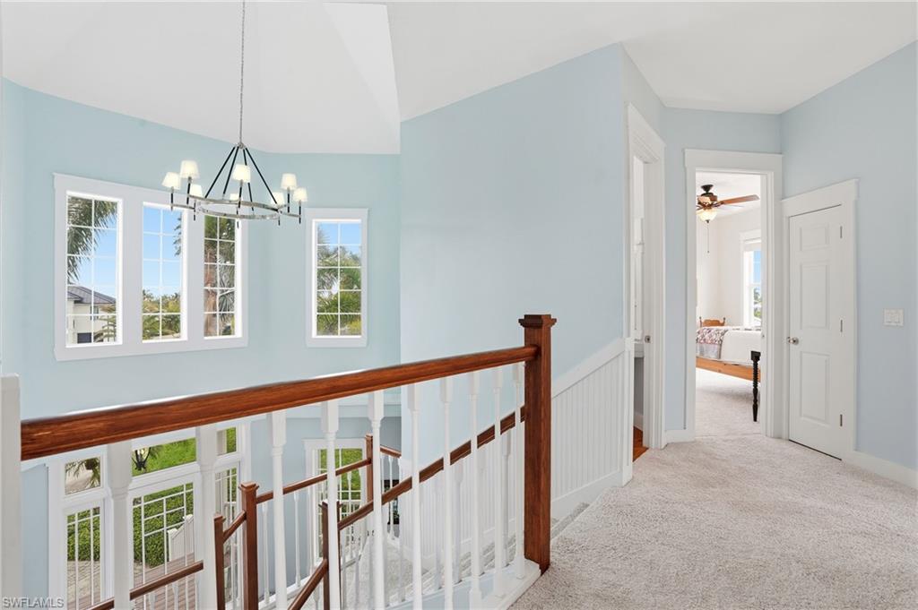 Hall featuring carpet, healthy amount of natural light, an upstairs landing, and a chandelier