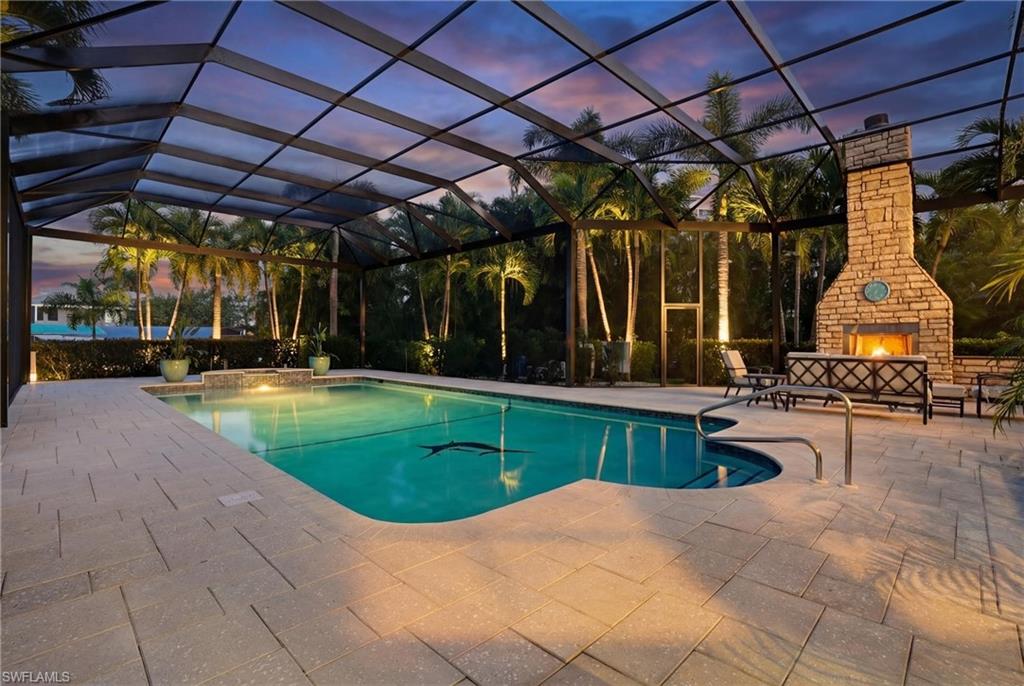 Outdoor pool with glass enclosure, an outdoor stone fireplace, a patio, and a sunroom