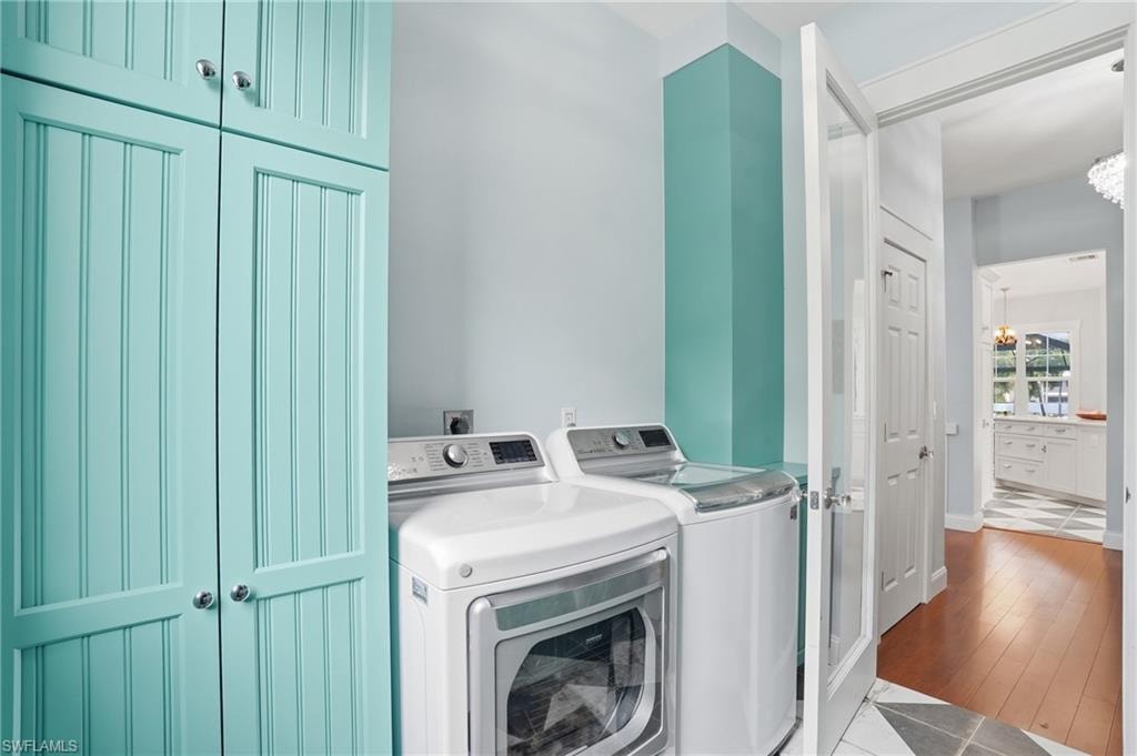 Laundry room with washer and clothes dryer, a chandelier, and wood finished floors