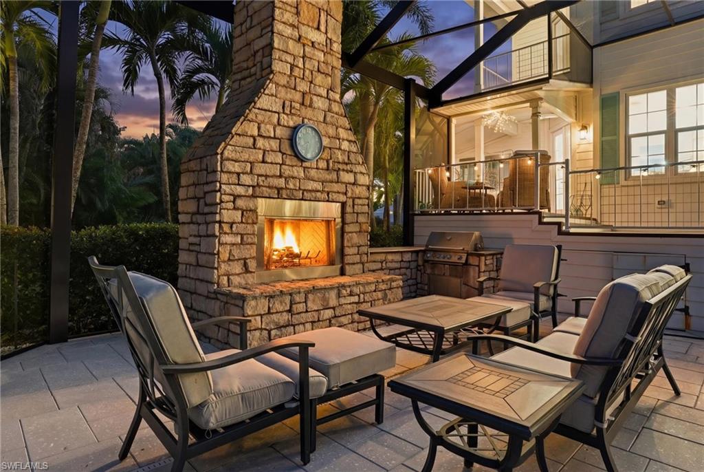 View of patio with a sunroom, an outdoor stone fireplace, a lanai, and an outdoor kitchen with living area