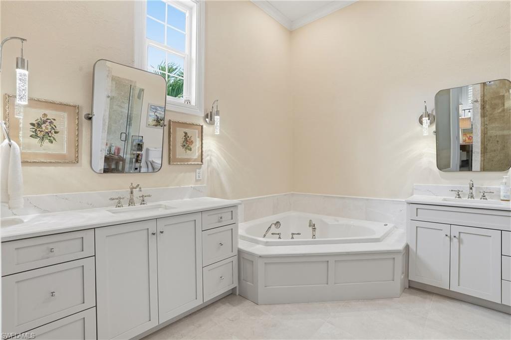 Bathroom featuring a garden tub, two vanities, and ornamental molding