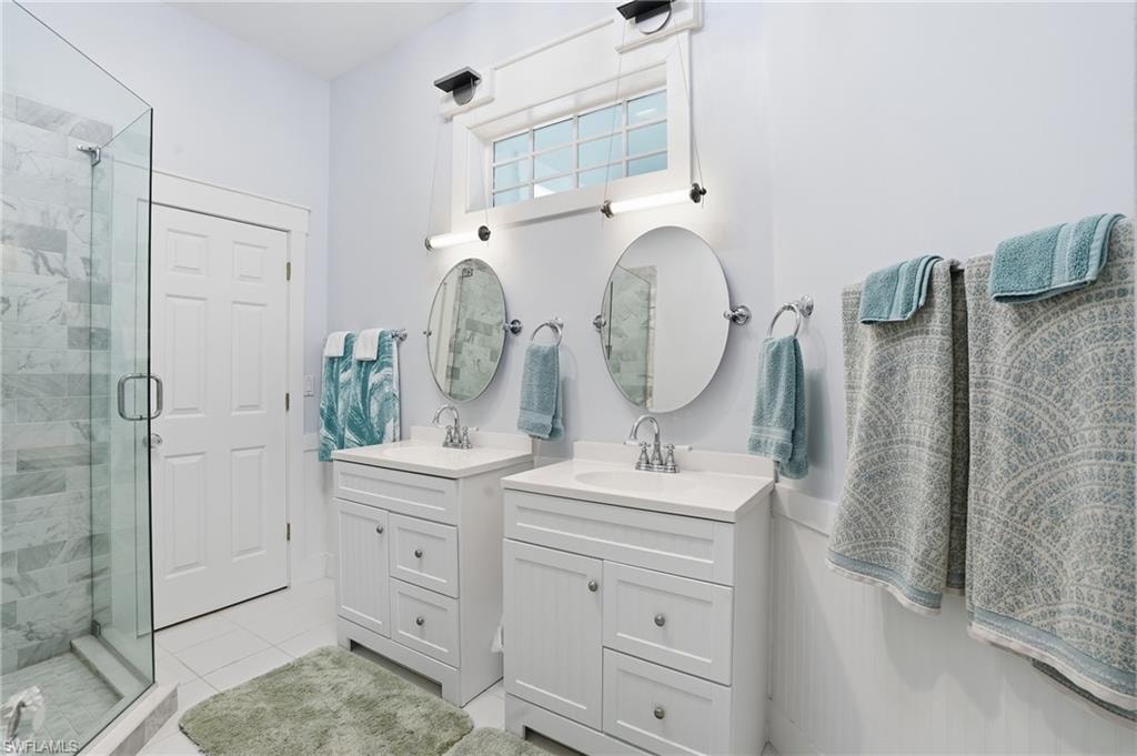Bathroom with two vanities, a shower stall, and light tile patterned floors