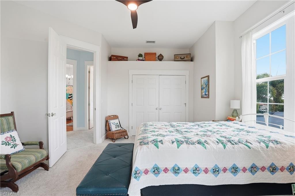 Bedroom featuring light colored carpet, a closet, and ceiling fan