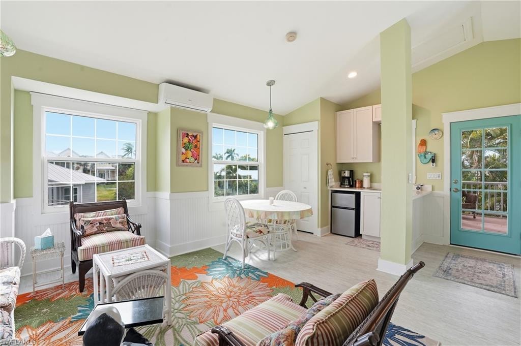 Living area featuring wainscoting, vaulted ceiling, a wall mounted air conditioner, recessed lighting, and light wood finished floors