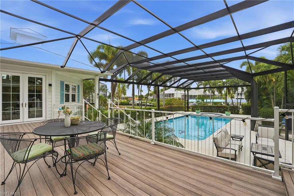 Wooden deck featuring french doors, an outdoor pool, a lanai, a sunroom, and outdoor dining space