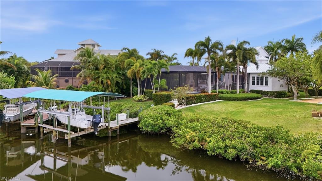 Dock area featuring a sunroom, boat lift, a water view, and a yard