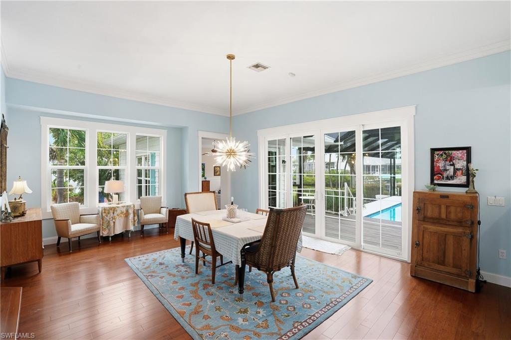 Dining space with dark wood-style floors, crown molding, and a chandelier
