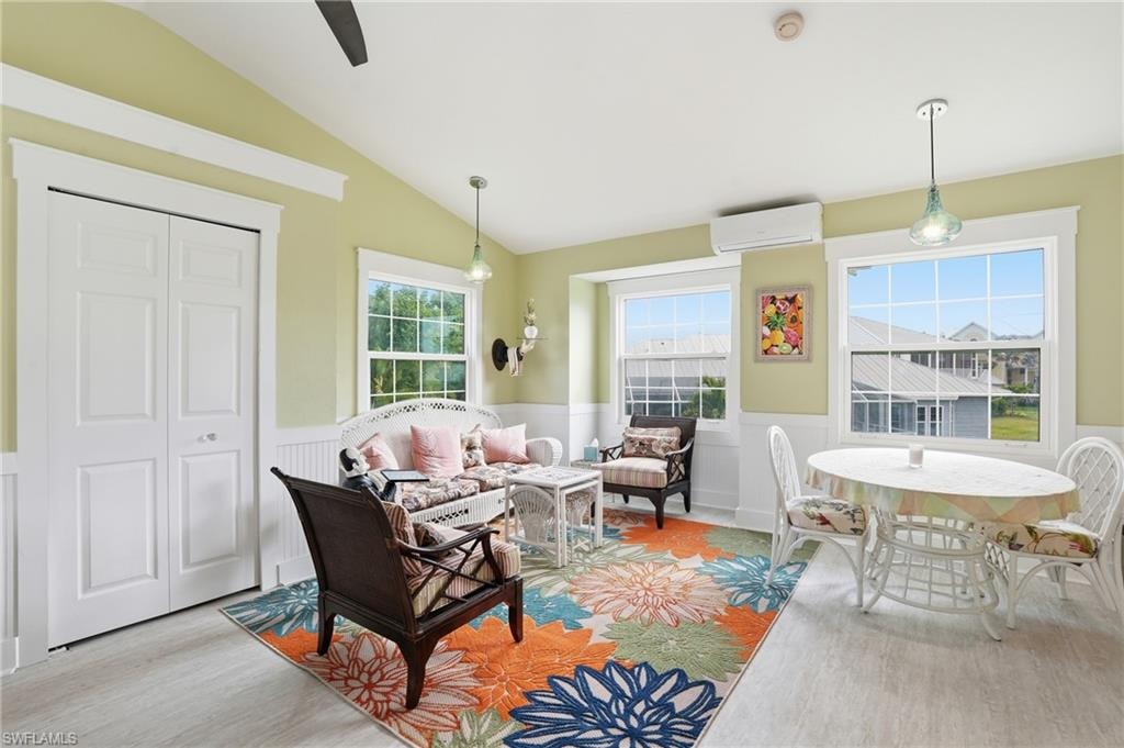 Living room featuring a wainscoted wall, wood finished floors, vaulted ceiling, and a wall mounted AC