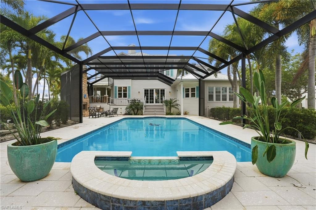 View of swimming pool with a pool with connected hot tub, a lanai, a sunroom, and a patio area