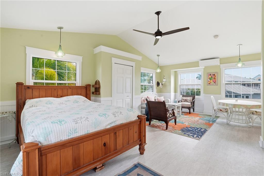 Bedroom with a wainscoted wall, a closet, wood finished floors, ceiling fan, and lofted ceiling