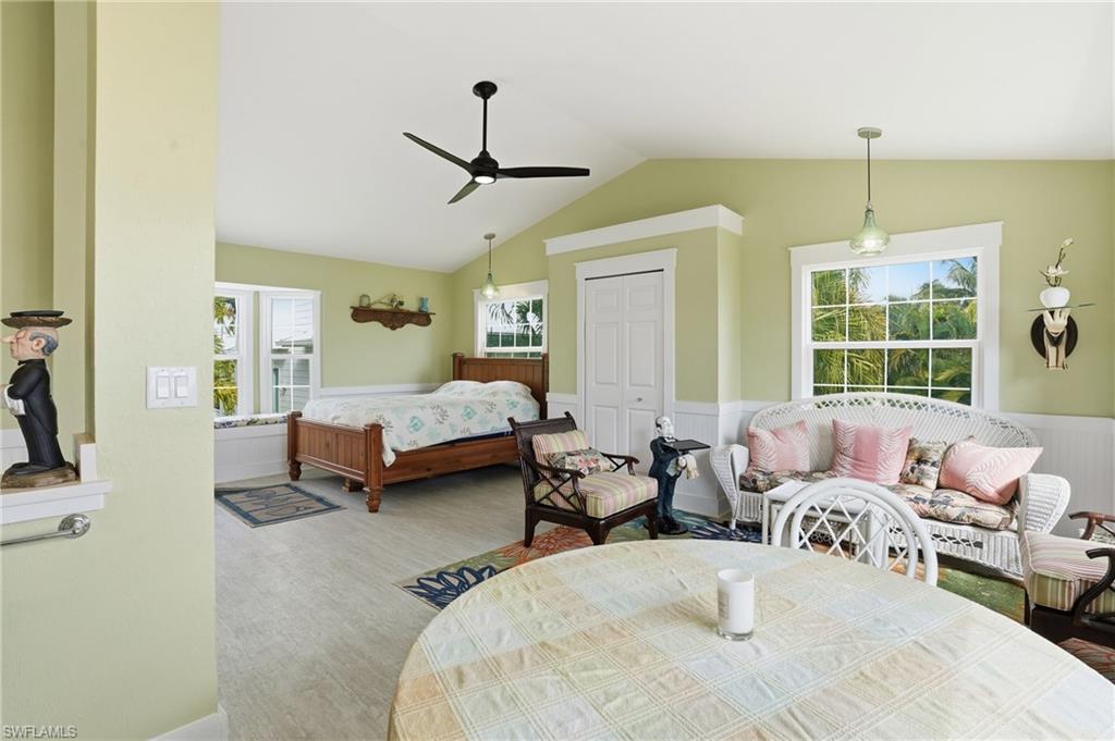 Bedroom featuring a closet, a wainscoted wall, a ceiling fan, vaulted ceiling, and wood finished floors