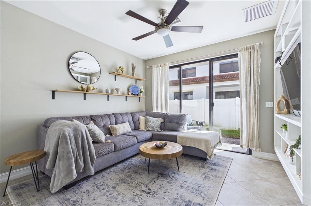 Living room with light tile patterned floors and a ceiling fan