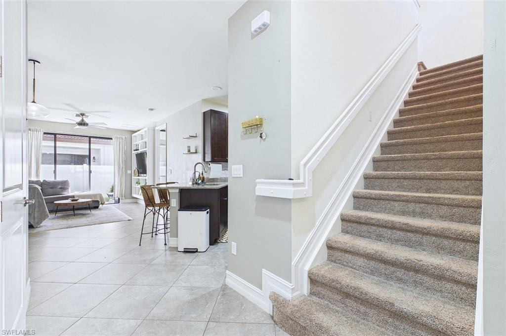 Stairs with tile patterned flooring and a ceiling fan
