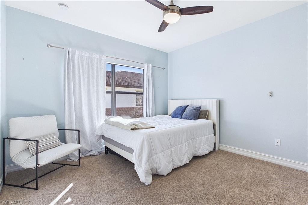 Carpeted bedroom with a ceiling fan and baseboards