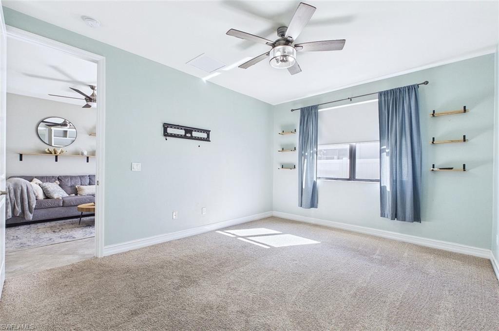 Carpeted empty room featuring ceiling fan and baseboards