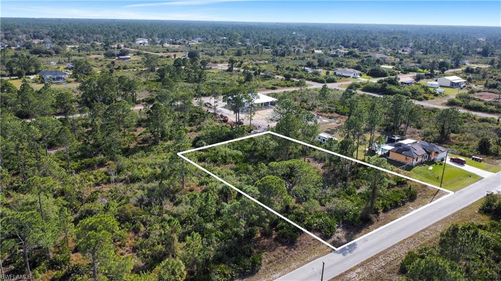 Aerial view of residential area featuring property boundaries highlighted and a heavily wooded area