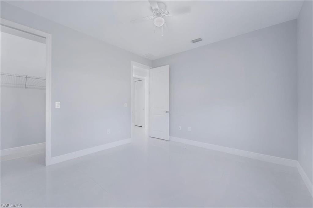 Unfurnished bedroom featuring a spacious closet and a ceiling fan