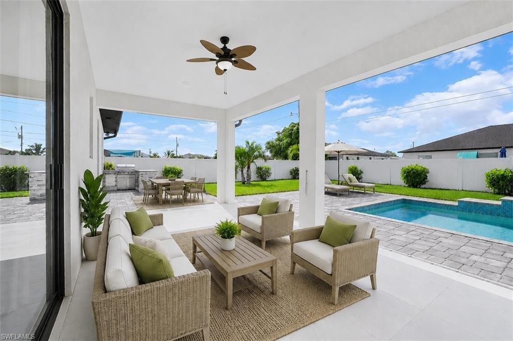 Covered patio featuring a ceiling fan and recessed lighting, with an outdoor kitchen, paver decking, and a swimming pool