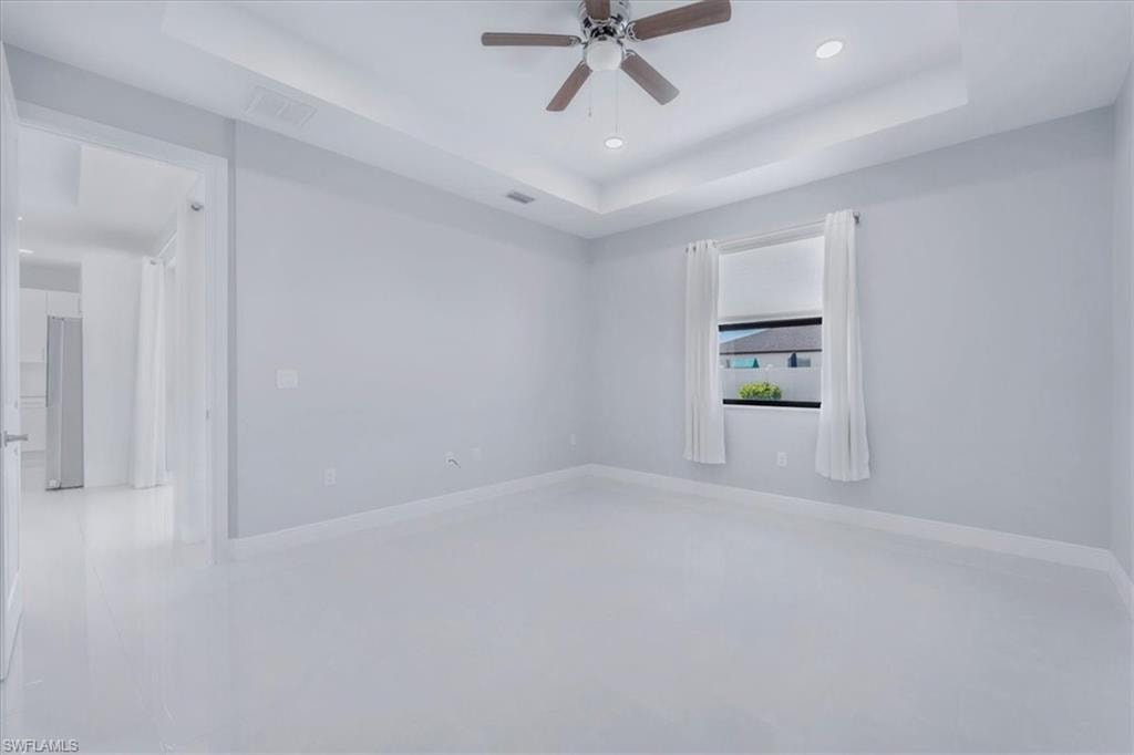 Unfurnished room with a raised ceiling, recessed lighting, and a ceiling fan