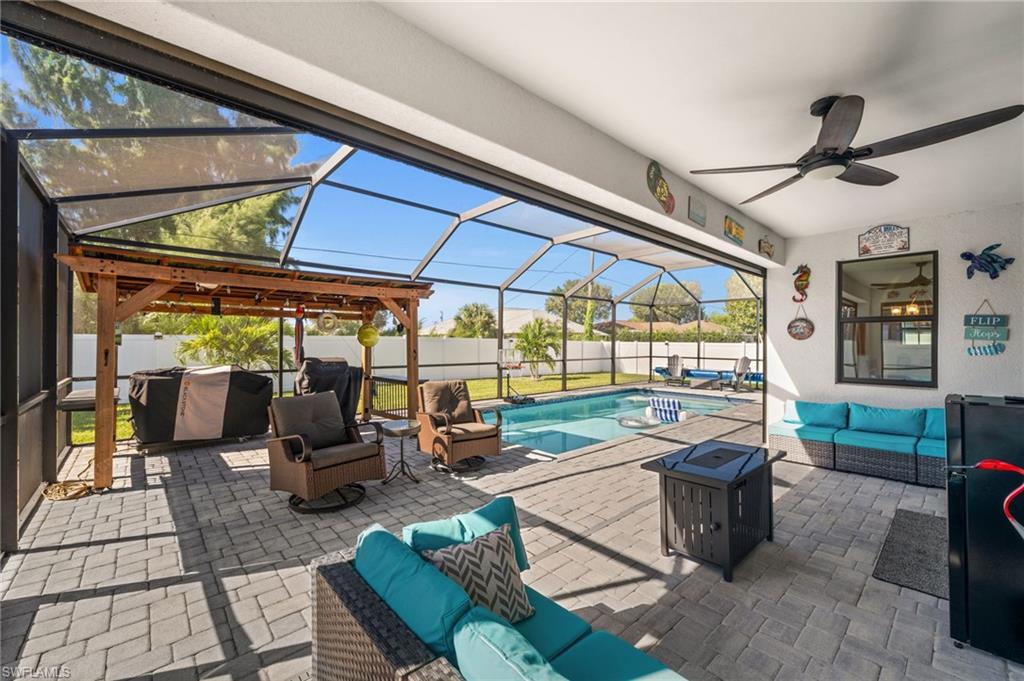 Fenced backyard featuring an outdoor living space with a fire pit, a sunroom, a patio, glass enclosure, and a ceiling fan