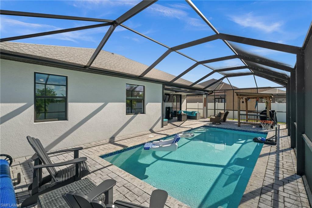 View of swimming pool with a sunroom, glass enclosure, a patio area, and outdoor lounge area