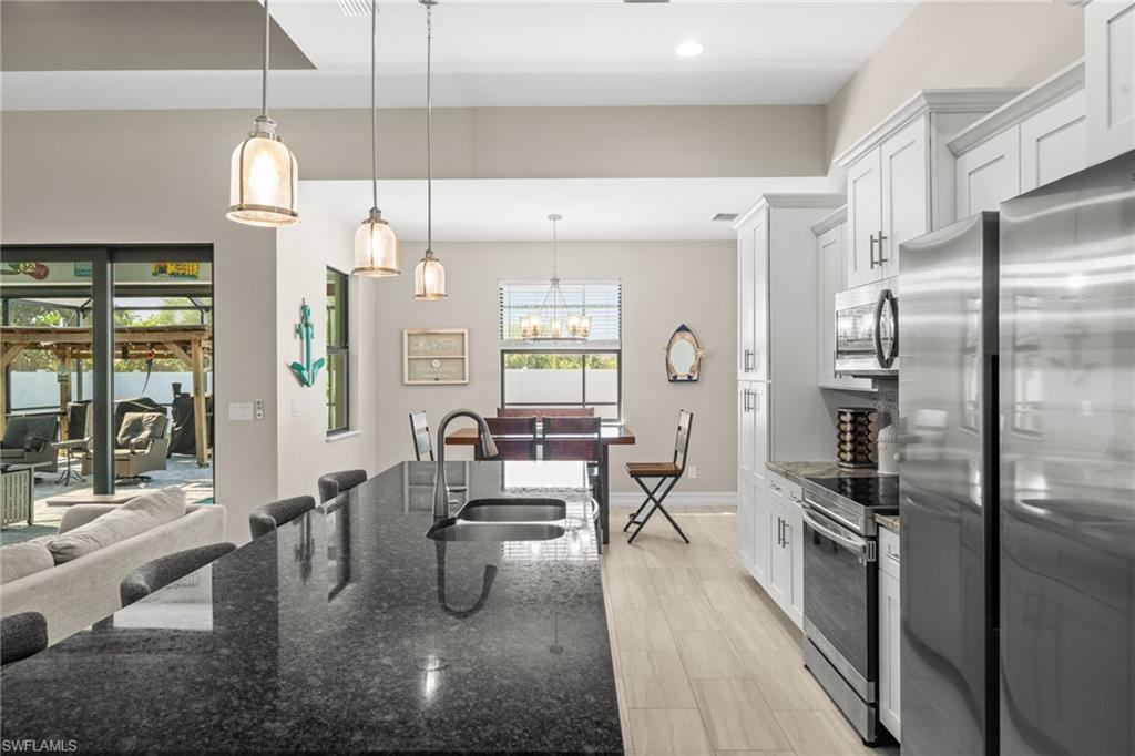 Kitchen with dark stone counters, pendant lighting, a breakfast bar area, stainless steel appliances, and white cabinets