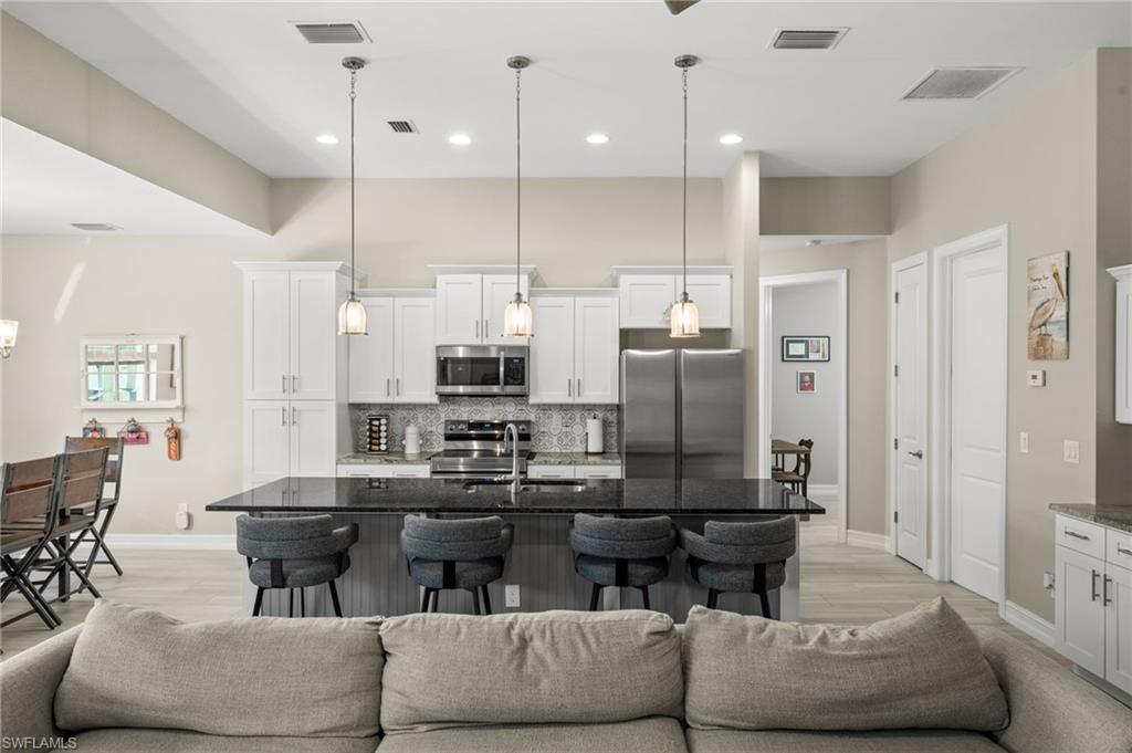 Kitchen with open floor plan, dark stone countertops, a kitchen breakfast bar, appliances with stainless steel finishes, and a high ceiling