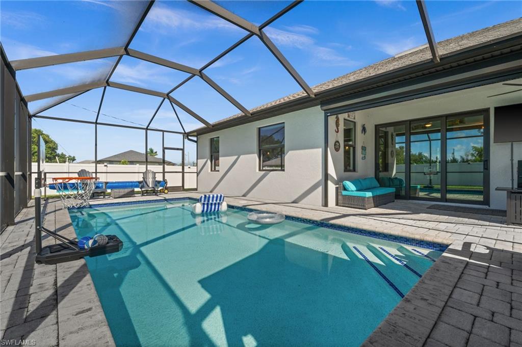 View of swimming pool with a sunroom, a patio area, and glass enclosure