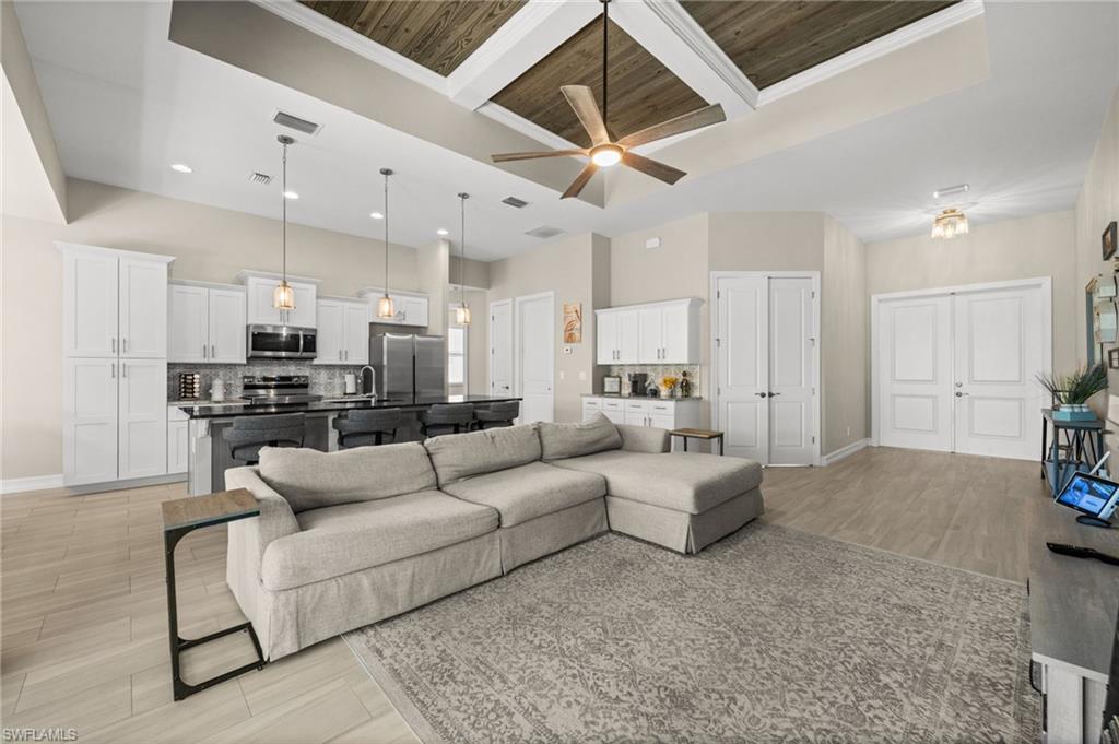 Living area featuring wood tiled floors, crown molding, a wood ceiling with exposed beams, coffered ceiling, and ceiling fan