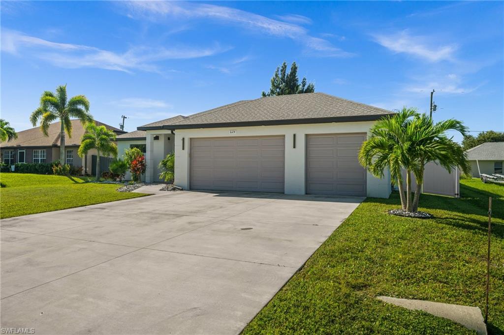 Ranch-style home with a front lawn, concrete driveway, stucco siding, a garage, and roof with shingles