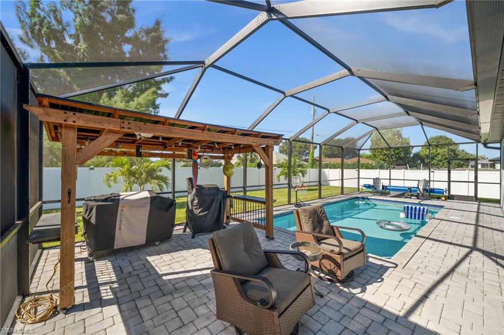 View of pool featuring a sunroom, a patio area, a lanai, a grill, and a fenced backyard