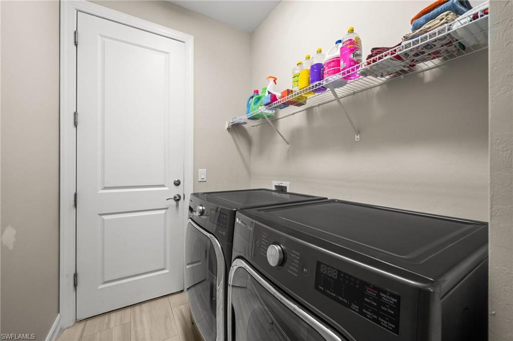 Laundry room with washing machine and dryer and light wood-style flooring