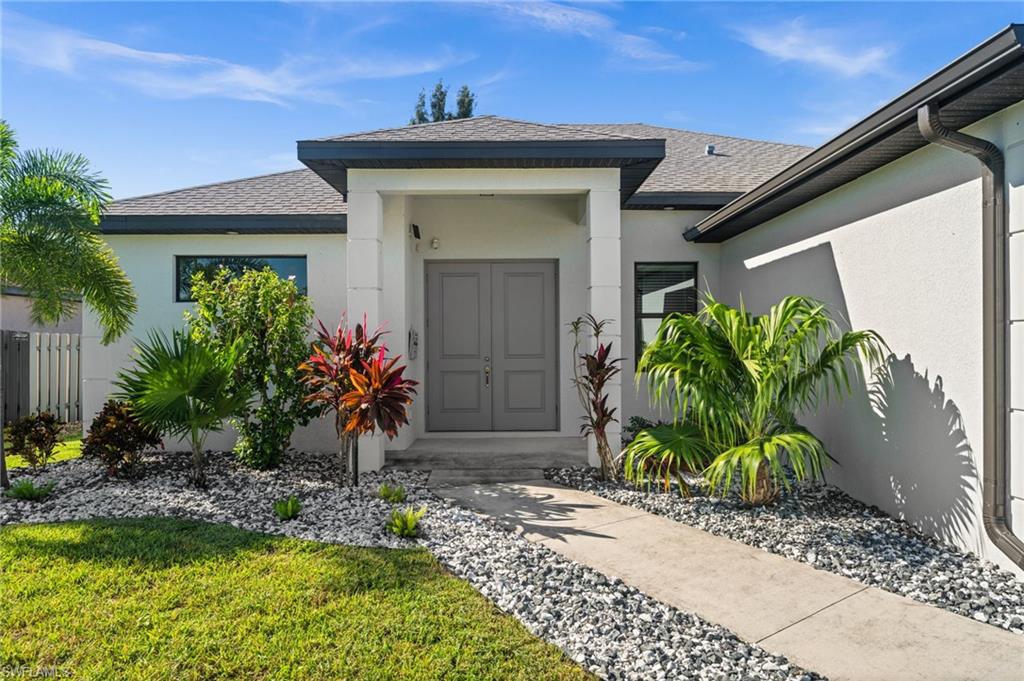 Doorway to property with a shingled roof and stucco siding
