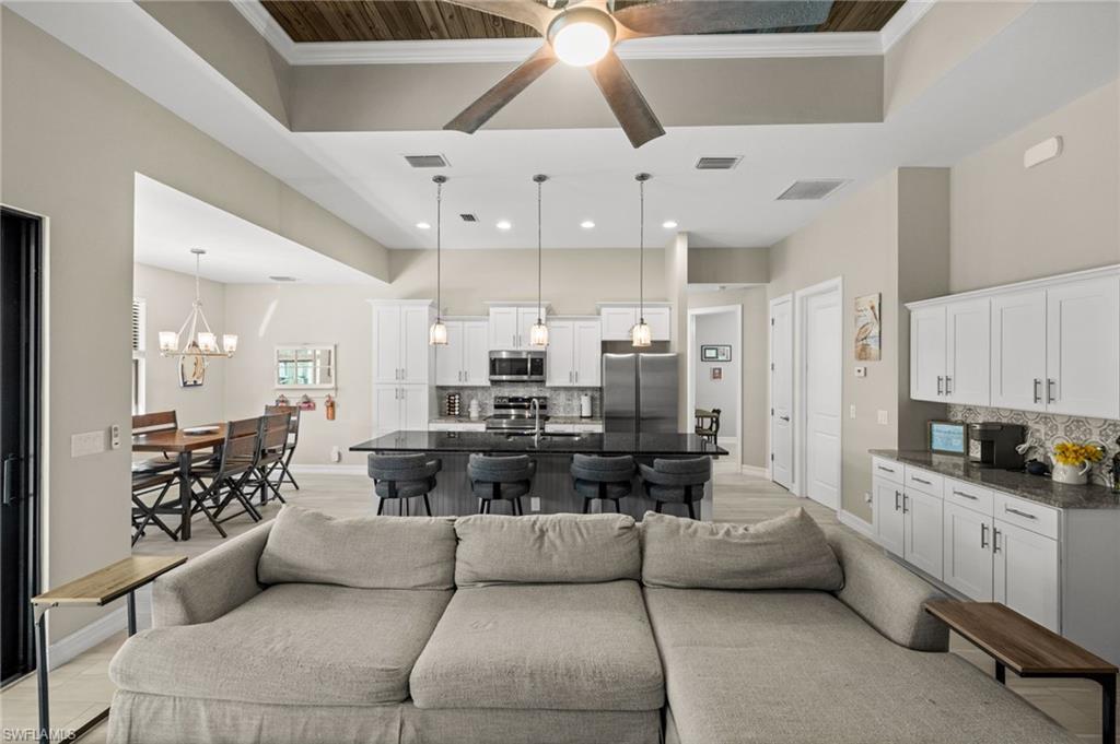 Living area featuring ornamental molding, a chandelier, a ceiling fan, and a high ceiling