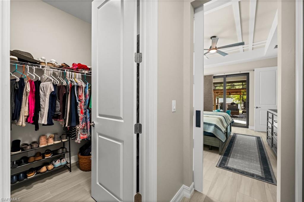 Walk in closet featuring coffered ceiling, ceiling fan, light wood-style flooring, and beam ceiling
