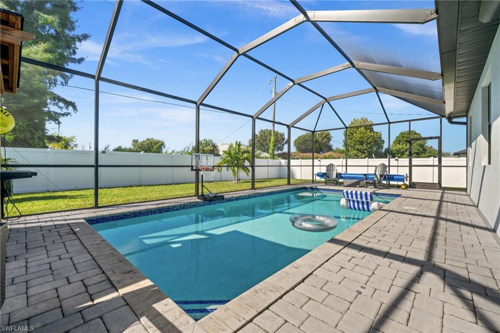 View of pool with glass enclosure, a sunroom, a patio, and a fenced backyard