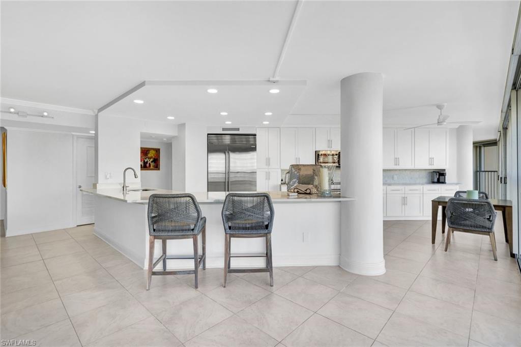 Kitchen with white cabinetry, tasteful backsplash, light tile patterned floors, appliances with stainless steel finishes, and ceiling fan