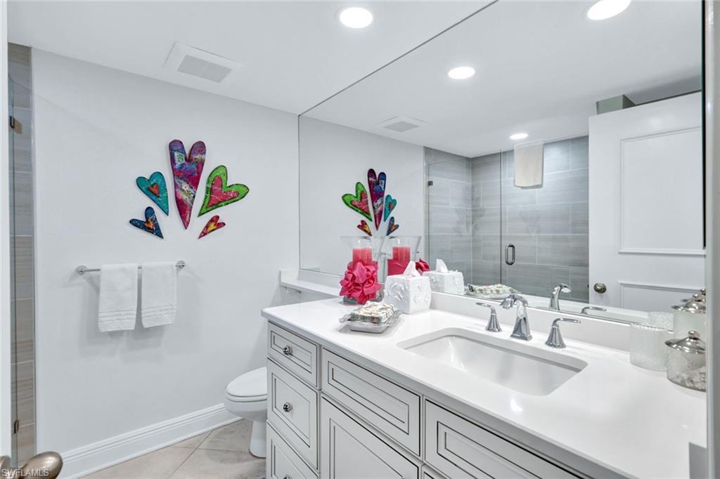 Bathroom with vanity, toilet, a shower with shower door, and tile patterned flooring