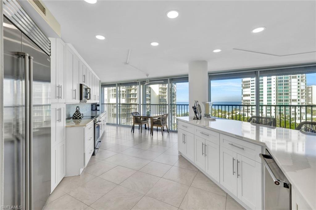 Kitchen featuring high quality appliances, expansive windows, light tile patterned floors, and white cabinets