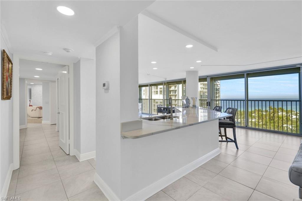 Kitchen featuring sink, light tile patterned floors, a wall of windows, a water view, and kitchen peninsula