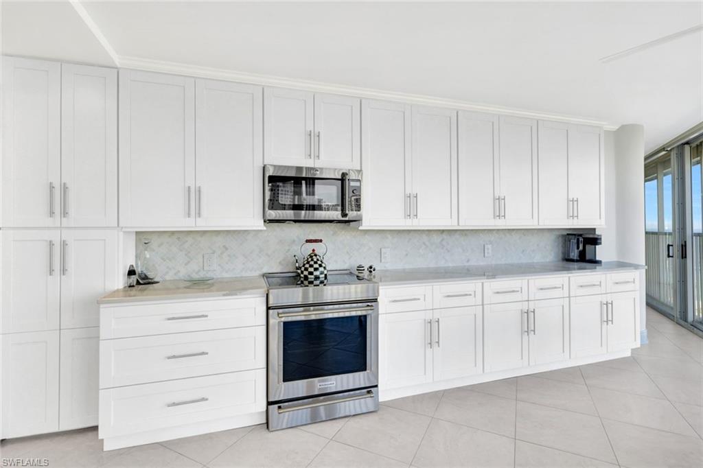 Kitchen featuring tasteful backsplash, appliances with stainless steel finishes, light tile patterned flooring, and white cabinets