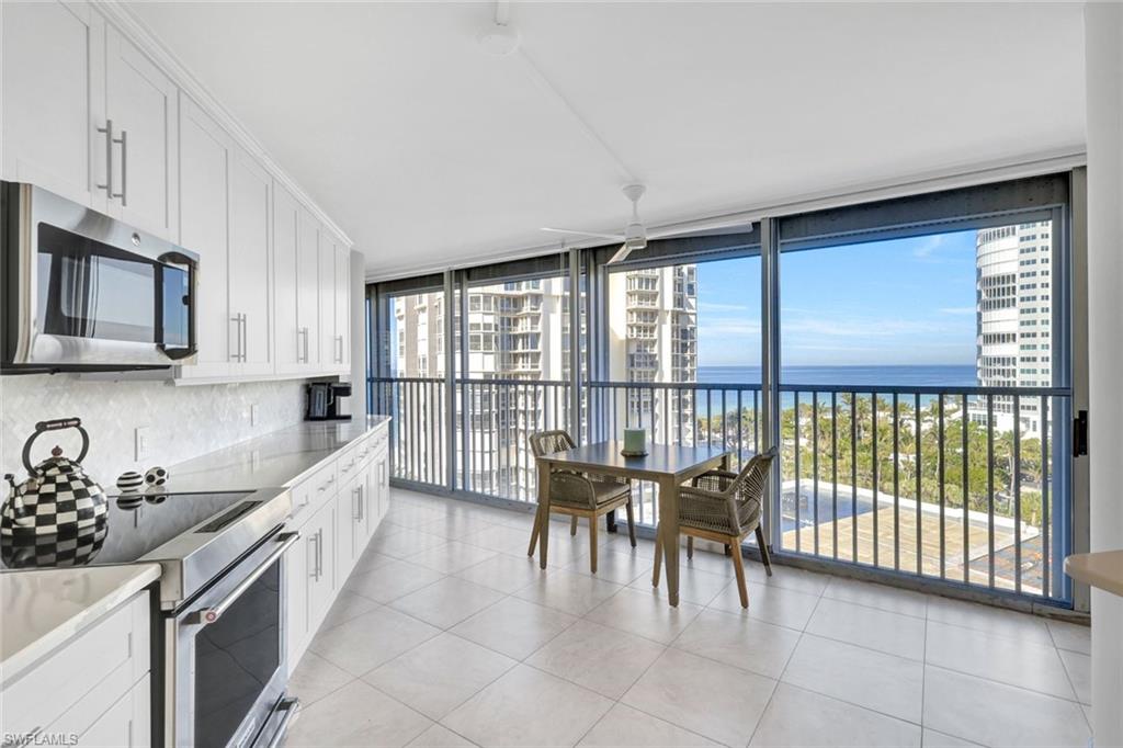 Kitchen with a wall of windows, white cabinetry, stainless steel appliances, a water view, and decorative backsplash
