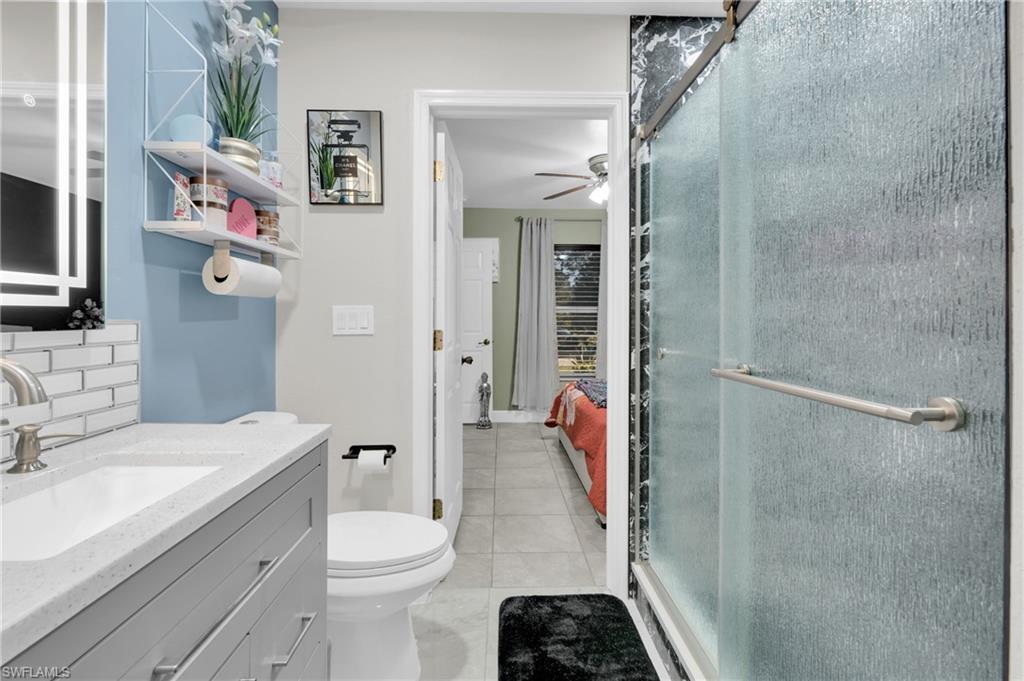 Ensuite bathroom with vanity, a stall shower, backsplash, and light tile patterned floors