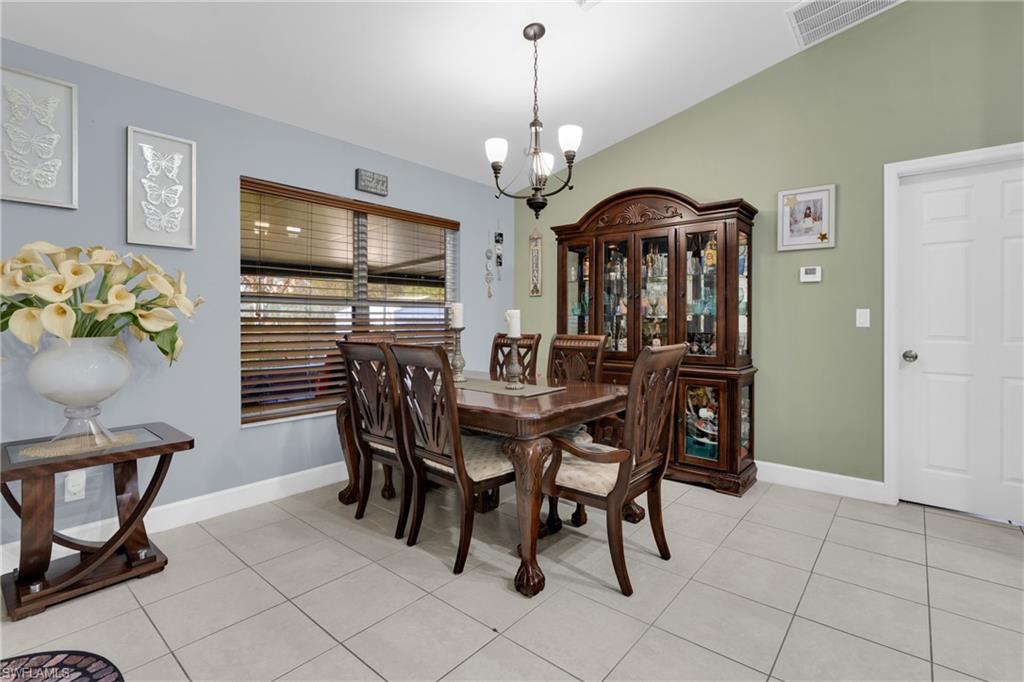 Dining area featuring a chandelier, light tile patterned floors, and vaulted ceiling