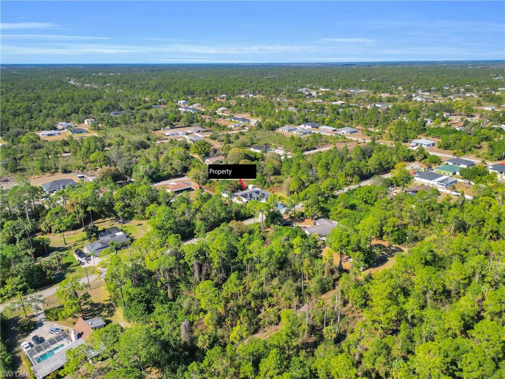 Aerial view of property and surrounding area with a forest