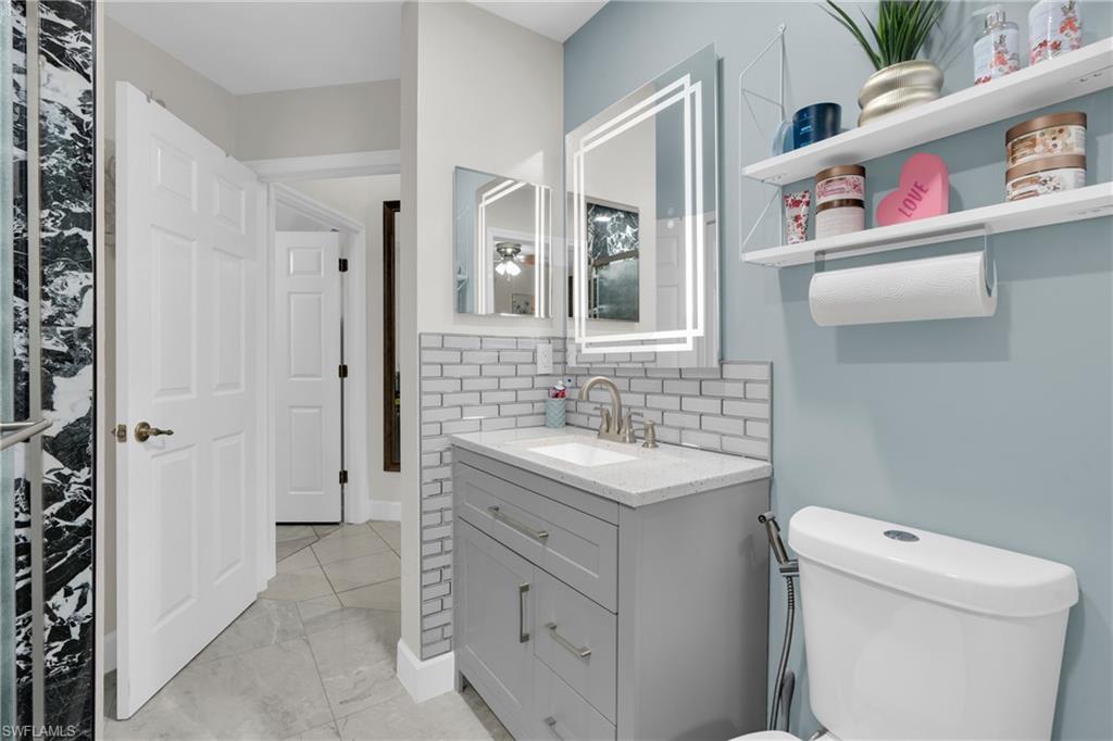 Half bath with vanity and tasteful backsplash