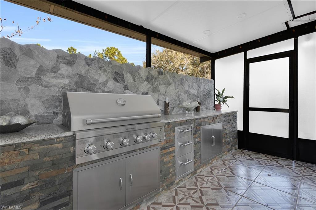 View of patio / terrace featuring an outdoor kitchen and a sunroom