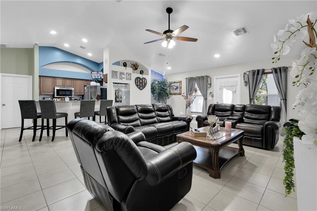 Living area with a ceiling fan, recessed lighting, light tile patterned floors, and lofted ceiling